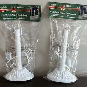 以下が含まれることがあります： 透明な電球と白いコードが付いた、白い伝統的なプラグインキャンドルランプが2つ。ランプは、緑と白のラベルが付いた透明なビニール袋に包装されています。ラベルには「伝統的なプラグインキャンドルランプ」と書いてあります。