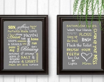 May include: Two framed prints with gray backgrounds and yellow text. The left print has a word cloud of positive attributes for a son. The right print has a list of bathroom rules for children. Both prints have a gray frame.