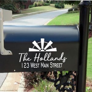 May include: Black mailbox with a white vinyl decal featuring a stylized sun design, the text "The Hollands" and the address "123 West Main Street".