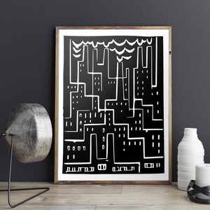 May include: Black and white abstract art print of a cityscape. The artwork features a minimalist design with white lines depicting buildings and smokestacks against a black background. The print is framed in a wooden frame.