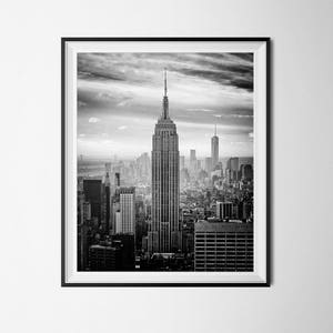 May include: A black and white photograph of the New York City skyline, featuring the Empire State Building in the center.