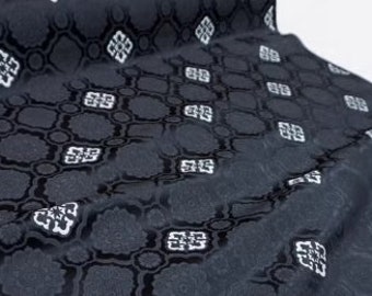 Könnte beinhalten: Schwarzer Stoff mit einem weißen geometrischen Muster. Der Stoff hat einen dezenten Glanz und eine strukturierte Oberfläche.