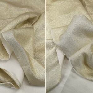 May include: A close-up of a gold fabric with a subtle shimmer. The fabric is folded and draped, showing its texture and drape.