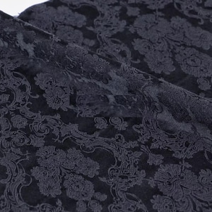 Pode incluir: Tecido azul marinho escuro com um padr&atilde;o floral e de rolagem detalhado. O tecido est&aacute; dobrado, mostrando a textura e profundidade do design. O padr&atilde;o &eacute; em um tom mais claro de azul marinho, criando um contraste sutil.