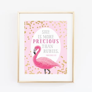 Może przedstawiać: Oprawiony wydruk z ilustracją różowego flaminga na różowym tle ze złotym konfetti. Tekst brzmi "SHE IS MORE PRECIOUS THAN RUBIES." Przysłowia 3:15 jest również wydrukowane.