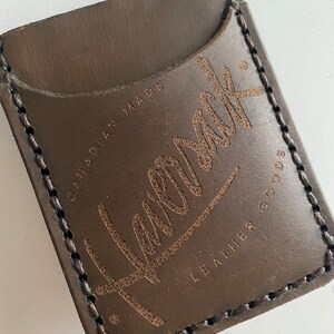 May include: A brown leather wallet with a stitched edge and the text "Havelock Leather Goods" and "Canadian Made" embossed on the front.
