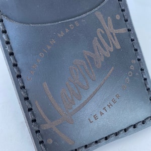 May include: Black leather card holder with a stitched edge and the text "Havensak: Leather Goods Canadian Made" embossed in gold.