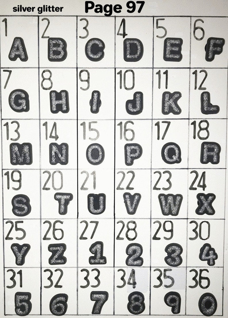 Puede incluir: Una cuadr&iacute;cula de cuadrados blancos con contornos negros, cada uno con un n&uacute;mero y una letra o n&uacute;mero. Las letras y los n&uacute;meros son de purpurina plateada. El texto "silver glitter" y "Page 97" est&aacute; en la parte superior.