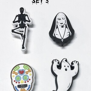 Op de afbeelding: Set van vier Halloween-schoenbedels. De bedels zijn een zwart-wit skelet, een witte non met een zwarte habit, een witte geest met zwarte contouren en een kleurrijke suiker schedel.