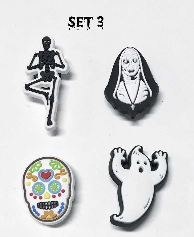 Op de afbeelding: Set van vier Halloween-schoenbedels. De bedels zijn een zwart-wit skelet, een witte non met een zwarte habit, een witte geest met zwarte contouren en een kleurrijke suiker schedel.