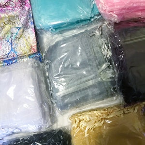 Puede incluir: Un surtido de cuadrados de tela transparente de colores, empaquetados en pl&aacute;stico transparente. Los colores incluyen rosa, azul, blanco, gris, negro y dorado. Algunas telas tienen dise&ntilde;os decorativos, como ramas o mariposas.