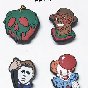 Op de afbeelding: Set van vier Halloween-schoenbedels. De bedels zijn gemaakt van rubber en tonen een groene vergiftigde appel, een rood-groene Freddy Krueger, een wit-blauwe Michael Myers en een rood-blauwe Pennywise.