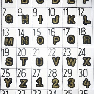 Puede incluir: Una cuadr&iacute;cula de letras del alfabeto y n&uacute;meros negros, cada uno con relleno de purpurina dorada. El texto "gold glitter" y "Page 97A" est&aacute;n en la parte superior. Las letras son de la A a la Z.