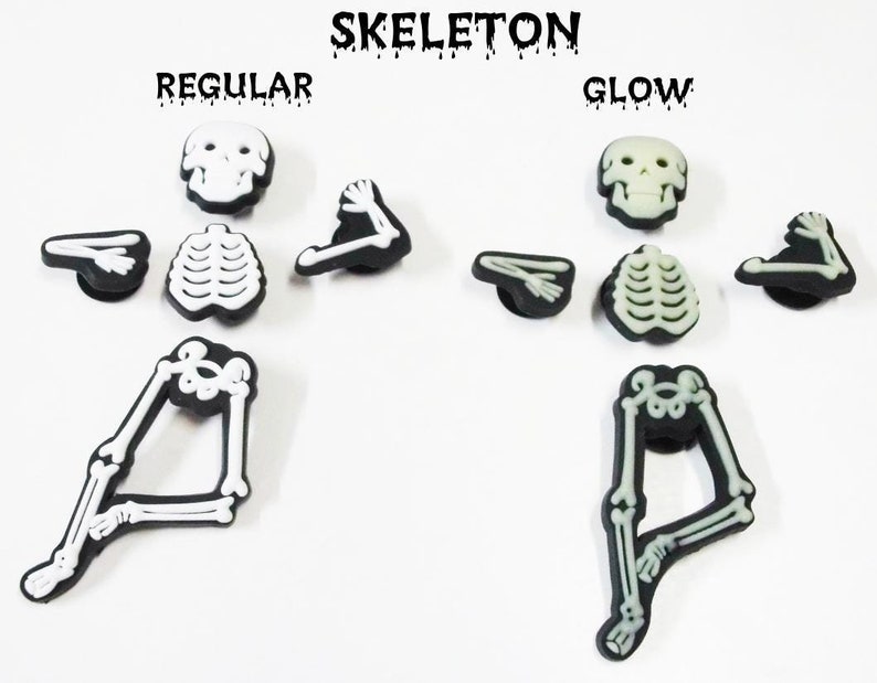 Op de afbeelding: Twee sets skelet-schoenbedels, &eacute;&eacute;n set is wit en de andere set gloeit in het donker. De bedels zijn gemaakt van plastic en zijn gevormd als een skelet. De bedels zijn gelabeld "Regular" en "Glow".