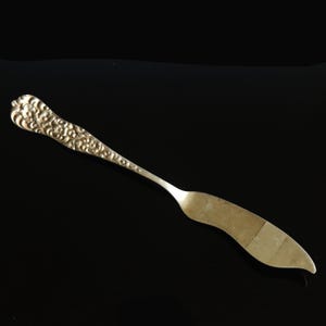 May include: A silver butter knife with an ornate, floral design on the handle.