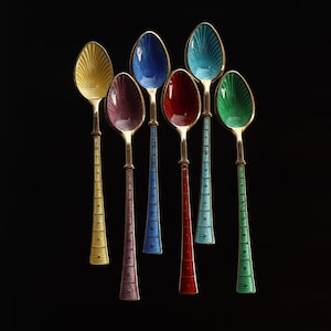May include: Seven colorful spoons with gold-colored handles and bowls. The bowls are painted in yellow, purple, blue, red, turquoise, and green. The handles are decorated with vertical lines and the bowls have a textured design.