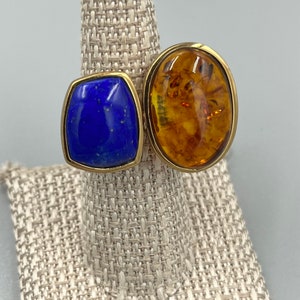 May include: A gold ring with two oval-shaped stones. The larger stone is amber and the smaller stone is blue lapis lazuli.