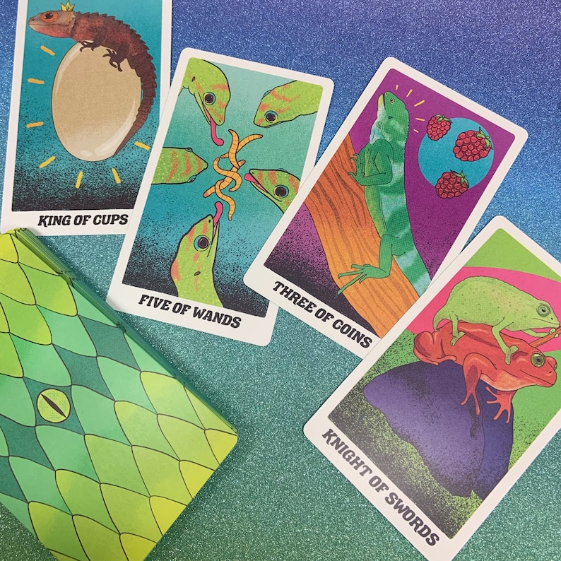 May include: Five tarot cards with colorful backgrounds and illustrations of lizards and other creatures. The cards are: King of Cups, Five of Wands, Three of Coins, Knight of Swords.