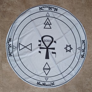 May include: A white circular cloth with black symbols and text, including a Star of David, an ankh, and the Hebrew word "10x0".