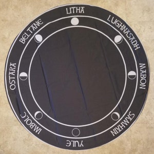 May include: A black circular tapestry with white text and moon symbols representing the eight sabbats of the Wheel of the Year. The sabbats are Yule, Imbolc, Ostara, Beltane, Litha, Lughnasadh, Mabon, and Samhain.