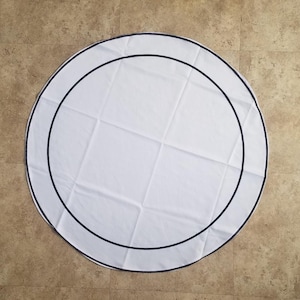 May include: White round tablecloth with a double black trim border.