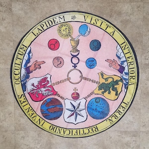 May include: A circular, yellow-bordered, pink and white design with the text "Visita Interiora Rectificando Invenies Occultum Lapidem" around the edge. The design features a central cross with a chalice, a sun, a moon, and other symbols.