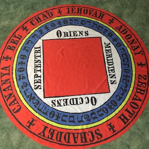 May include: A circular textile in red, white, blue, and yellow, with text and symbols. A red square is at the centre. The text includes the words "ORIENS", "SEPTENTRI", "MERIDIENS", and "OCCIDENS".