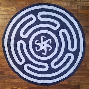 May include: A round, white and blue tapestry with a five-pointed star in the center and concentric circles radiating outwards.