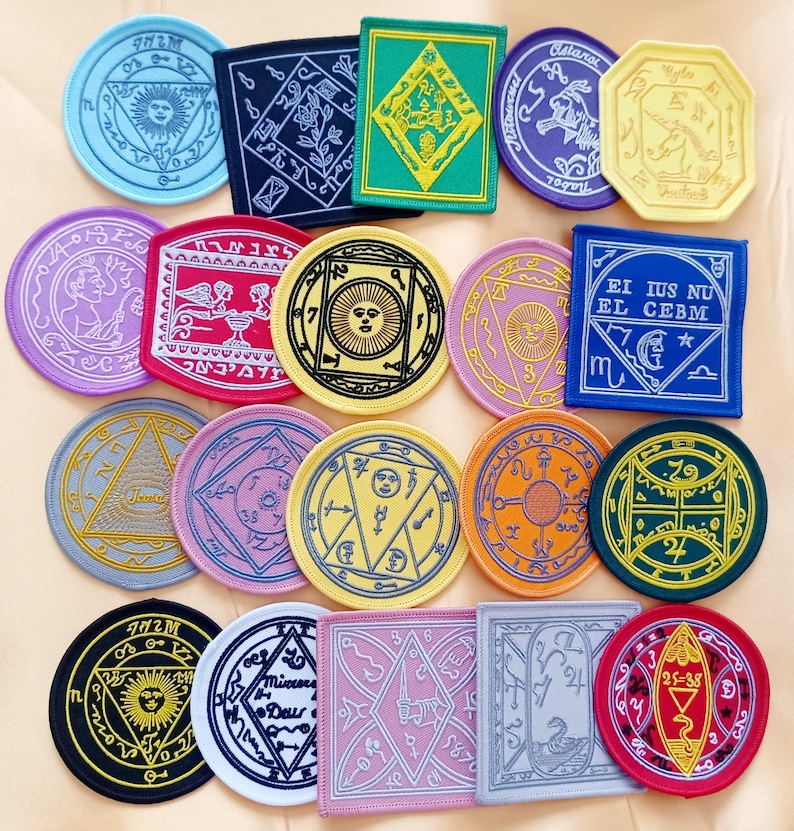May include: A collection of 16 embroidered patches featuring various symbols, designs, and text. The patches are circular, square, and octagonal in shape and come in a variety of colors, including red, blue, green, yellow, and gray. The patches feature intricate designs and text, including the words "EI IUS NU EL CEBM" and "Micrors Deur".