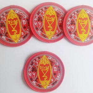 Peut inclure: Quatre patchs brod&eacute;s rouges avec un motif blanc et jaune. Le motif repr&eacute;sente un serpent, un triangle et le texte "25=38".