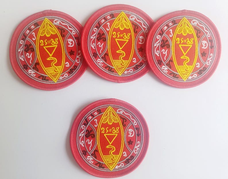 Peut inclure: Quatre patchs brod&eacute;s rouges avec un motif blanc et jaune. Le motif repr&eacute;sente un serpent, un triangle et le texte "25=38".
