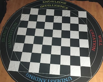 May include: A black and white checkered circular game board with the words "Knowledge", "Intelligence", "Silence", "Manifestation", "Will", "Creation", "Daring", "Understanding" printed around the edge.