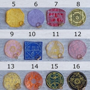 May include: A collection of twenty colorful, embroidered patches with various esoteric symbols and designs. Each patch has a metallic clasp. The patches are in various shapes, including squares, circles, and octagons.