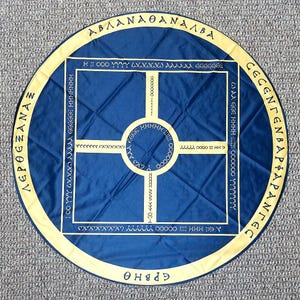 May include: A blue circular cloth with a yellow border and a pattern of letters and symbols in the center. The text around the border reads "ABLANAOANALBA" and "CECENΓΕΝΒΑΡΦΑΡΑΝΓΕΣ".