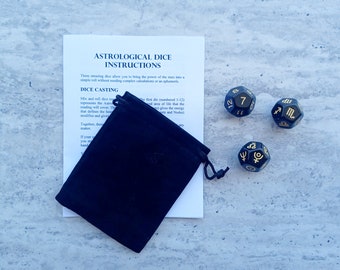 May include: Black astrological dice with gold zodiac symbols and numbers. The dice are in a black velvet pouch with instructions on a white sheet of paper.