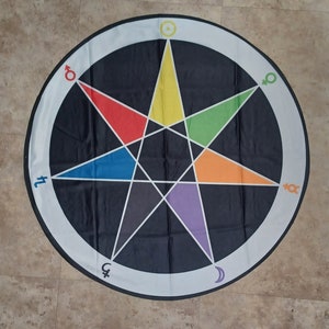 May include: A black and white circular tapestry with a seven-pointed star in the center. The star is divided into seven sections, each a different color: red, yellow, green, blue, purple, orange, and gray. The star is surrounded by a white circle with symbols around the edge.