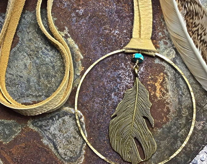 Going full circle large bronze hoop with hanging feather in center and a dab of turquoise with soft palomino elk leather