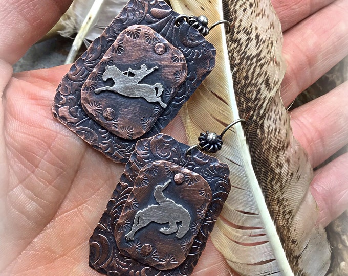 Ride em cowboy earrings by Weathered Soul saddle embossed rustic copper with a sterling silver different bronco on each earring, rodeo love