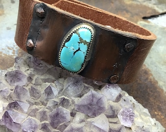 May include: A brown leather cuff bracelet with a turquoise stone set in silver. The bracelet has copper accents and is decorated with small metal studs.