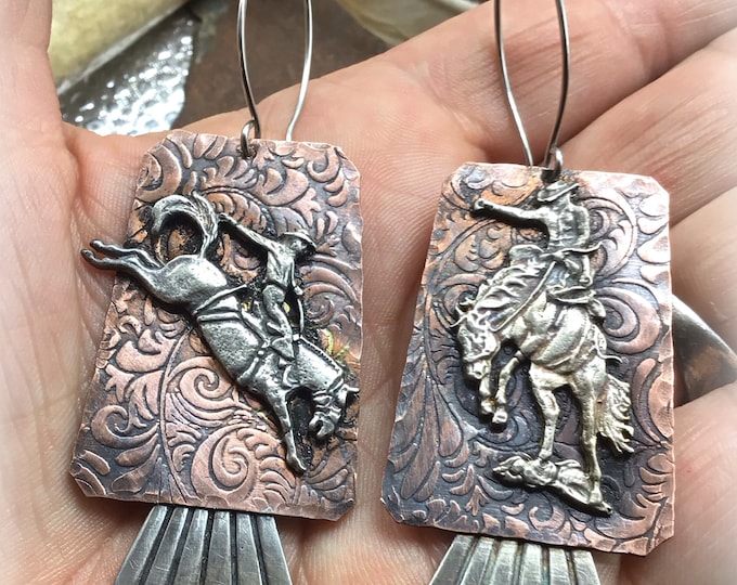 Ride em cowboy earrings by Weathered Soul saddle embossed rustic copper with a sterling silver different bronco on each earring, rodeo love