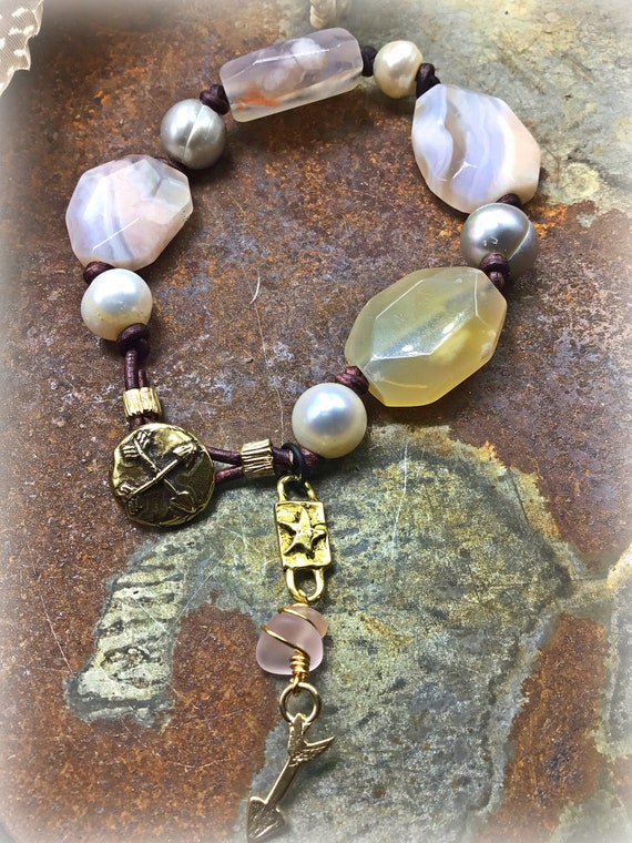 Peaches and cream agate, pearl, and leather knotted bracelet with bronze arrow and crossed arrow button closure