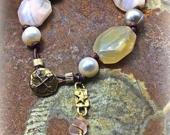 Peaches and cream agate, pearl, and leather knotted bracelet with bronze arrow and crossed arrow button closure