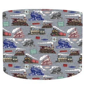May include: Grey fabric featuring a repeating pattern of vintage steam trains in red, blue, black, and yellow. The design includes text that reads "TO THE TRAINS" and "TO THE STATION". The trains are depicted with white smoke trails.