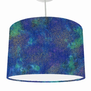 May include: A blue lampshade with a galaxy print and gold glitter. The lampshade is white on the inside.