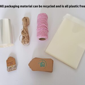 May include: A collection of packaging materials for gifts, including clear cellophane wrap, twine, brown paper gift tags, and a small bag. The text "Lavender Bag" is printed on one of the tags. All packaging materials are plastic-free and recyclable.