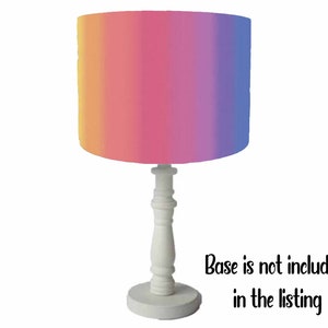 May include: A white table lamp with a pink, orange, and purple ombre lampshade. Base is not included in the listing.