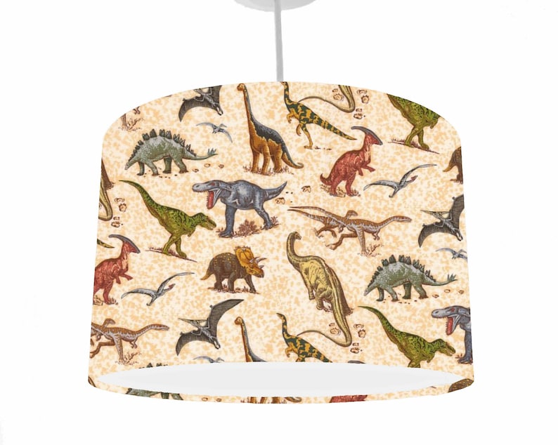May include: A beige lampshade with a dinosaur pattern. The dinosaurs are in various colors, including green, blue, red, and brown. The lampshade is perfect for a child's room.