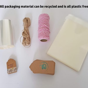 May include: A collection of packaging materials for gifts, including clear cellophane wrap, twine, brown paper gift tags, and a small bag. The text "Lavender Bag" is printed on one of the tags. All packaging materials are plastic-free and recyclable.