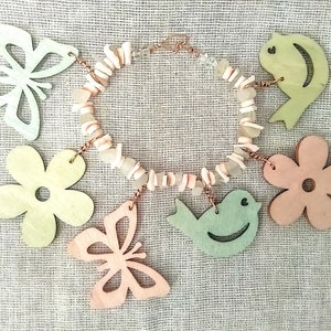 May include: A pastel-colored wooden necklace with a variety of charms, including butterflies, birds, and flowers. The necklace is made with natural materials and has a rustic, handmade look.