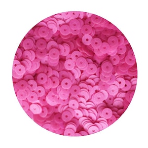 May include: A close-up image of a large pile of pink sequins. The sequins are round with a hole in the centre.
